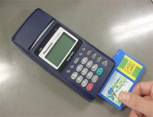 市役所税務課の受付端末でキャッシュカードを使い、市税等の口座振替手続きをしている写真